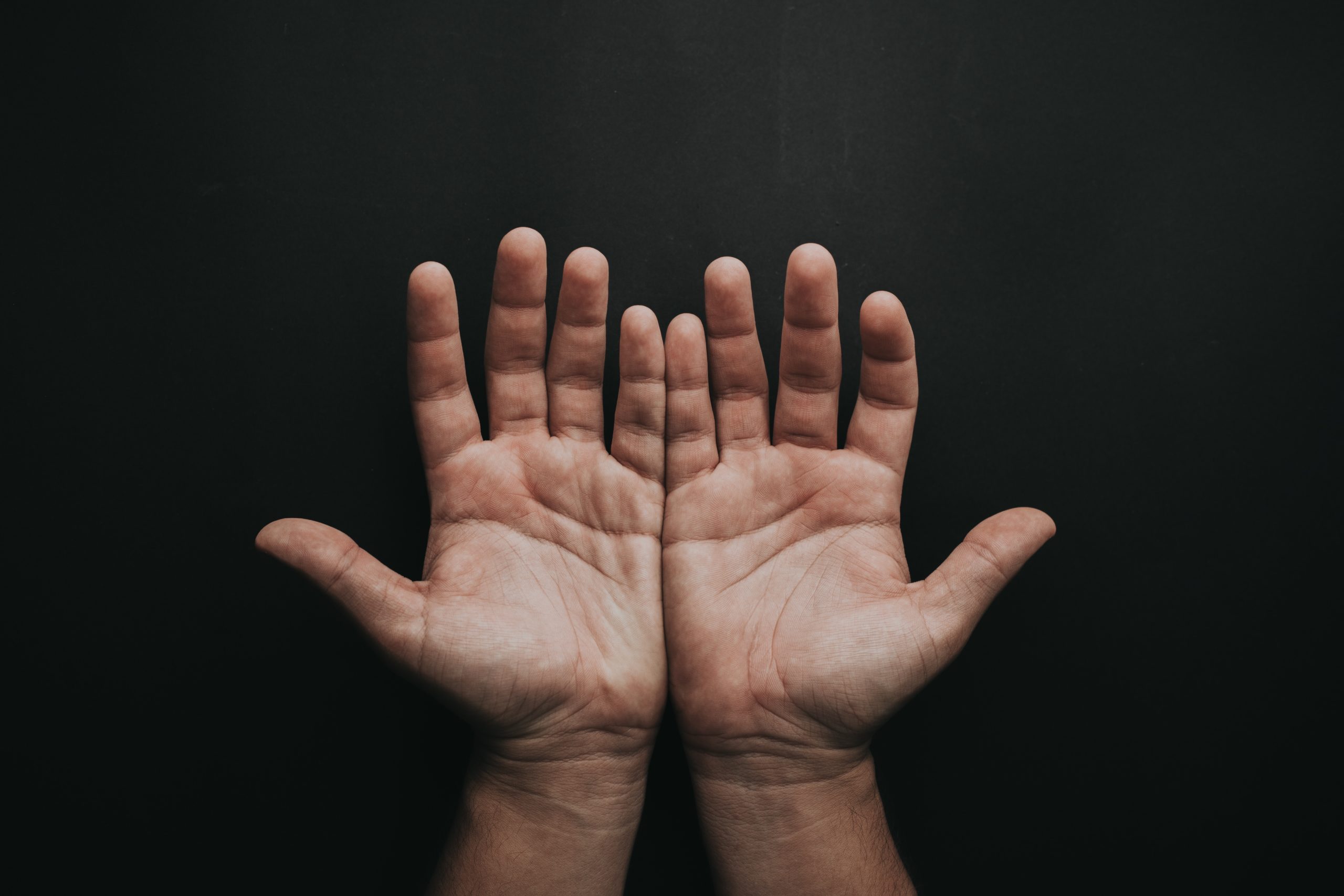 clean white males hands on a dark background with palms facing up