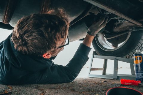 Mechanic performing repairs under a lifted car