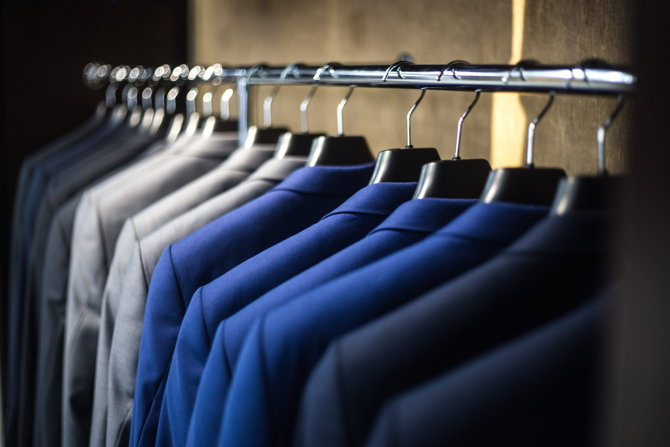 Row of blue and light gray suits hanging on a rack