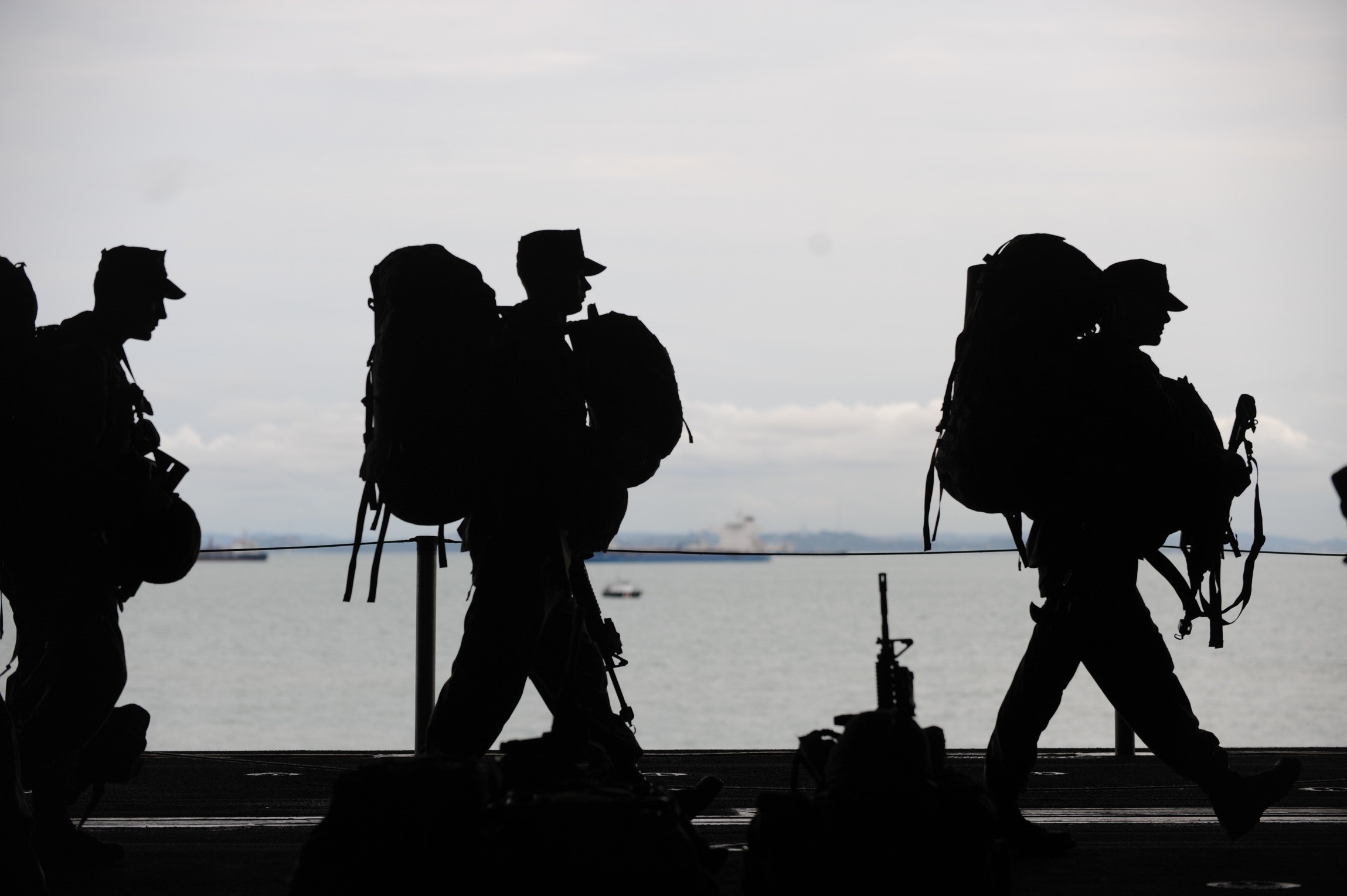 Military workers with travel gear walking in front of water