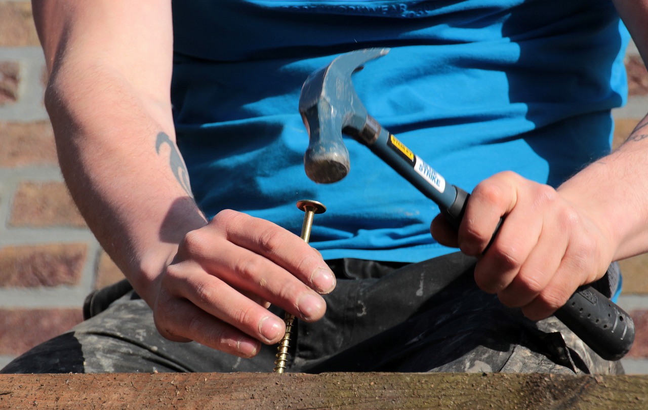 Man nails a screw with hammer