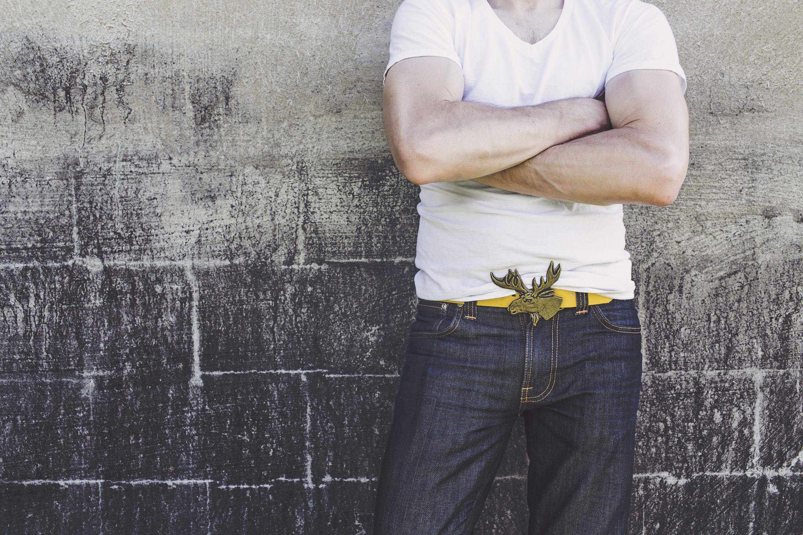 Man in white shirt with yellow belt leaning on wall