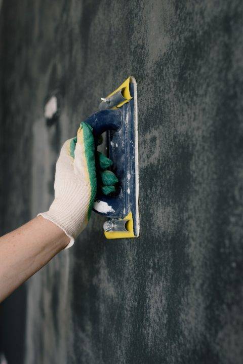 sanding a wall with a hand sander