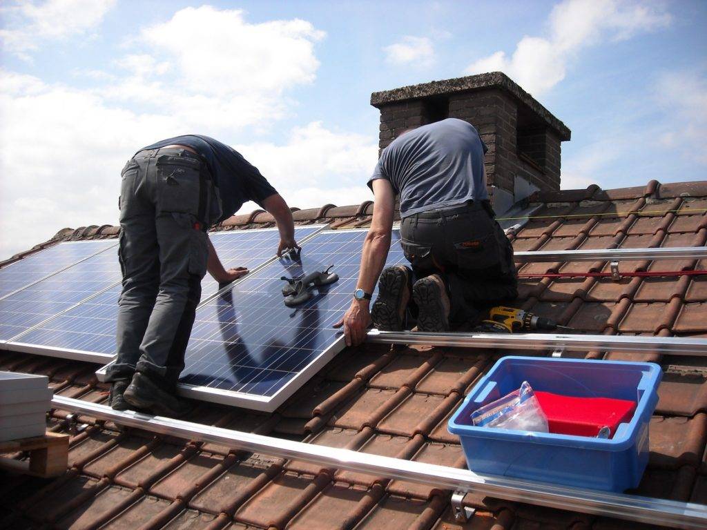 men installing solar panels onto a roof