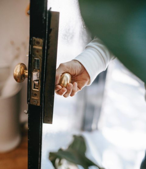 person using door knob to open door into home