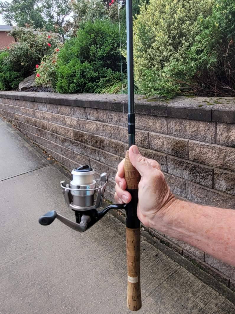 hand holding spinning reel fishing rod vertically