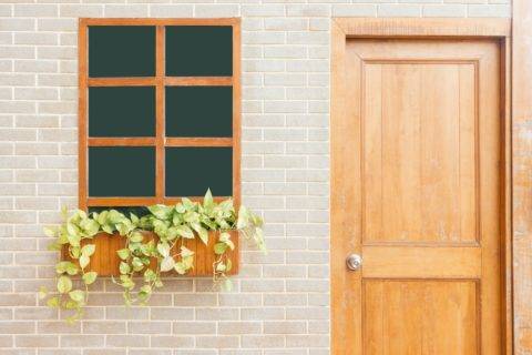 wooden front door next to window with flowers in planter box