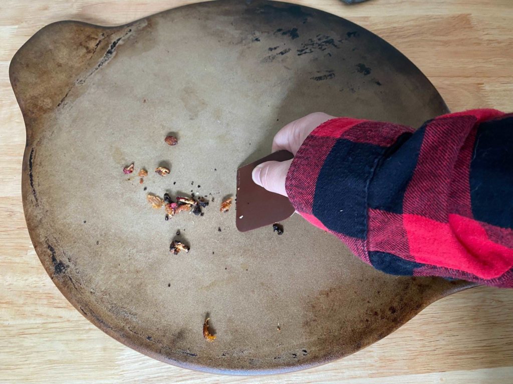 scraping debris and leftover grease from pizza stone