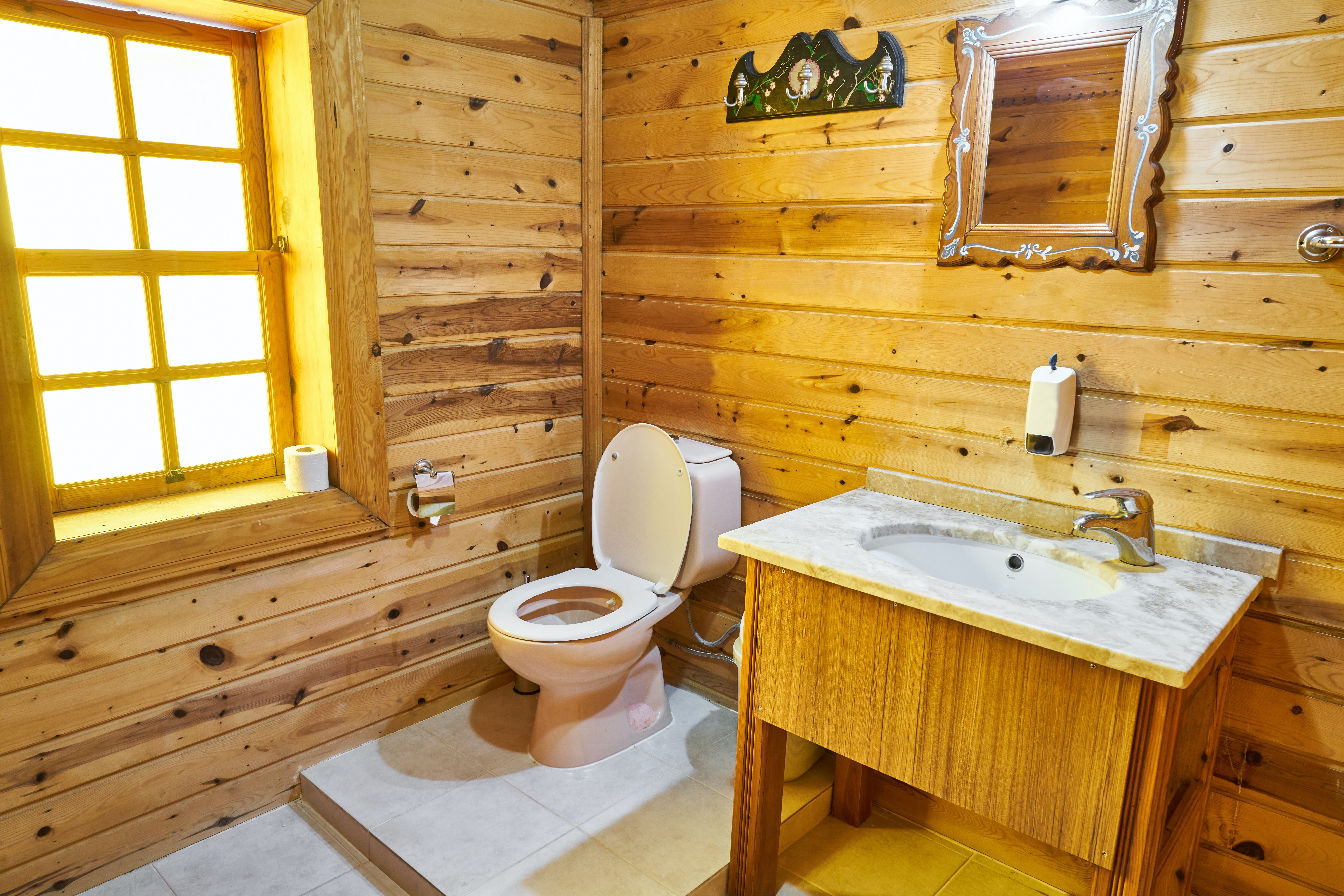 wood panelled bathroom with small sink and mirror
