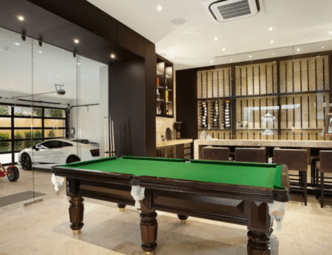 high-end man cave with pool table, bar and car