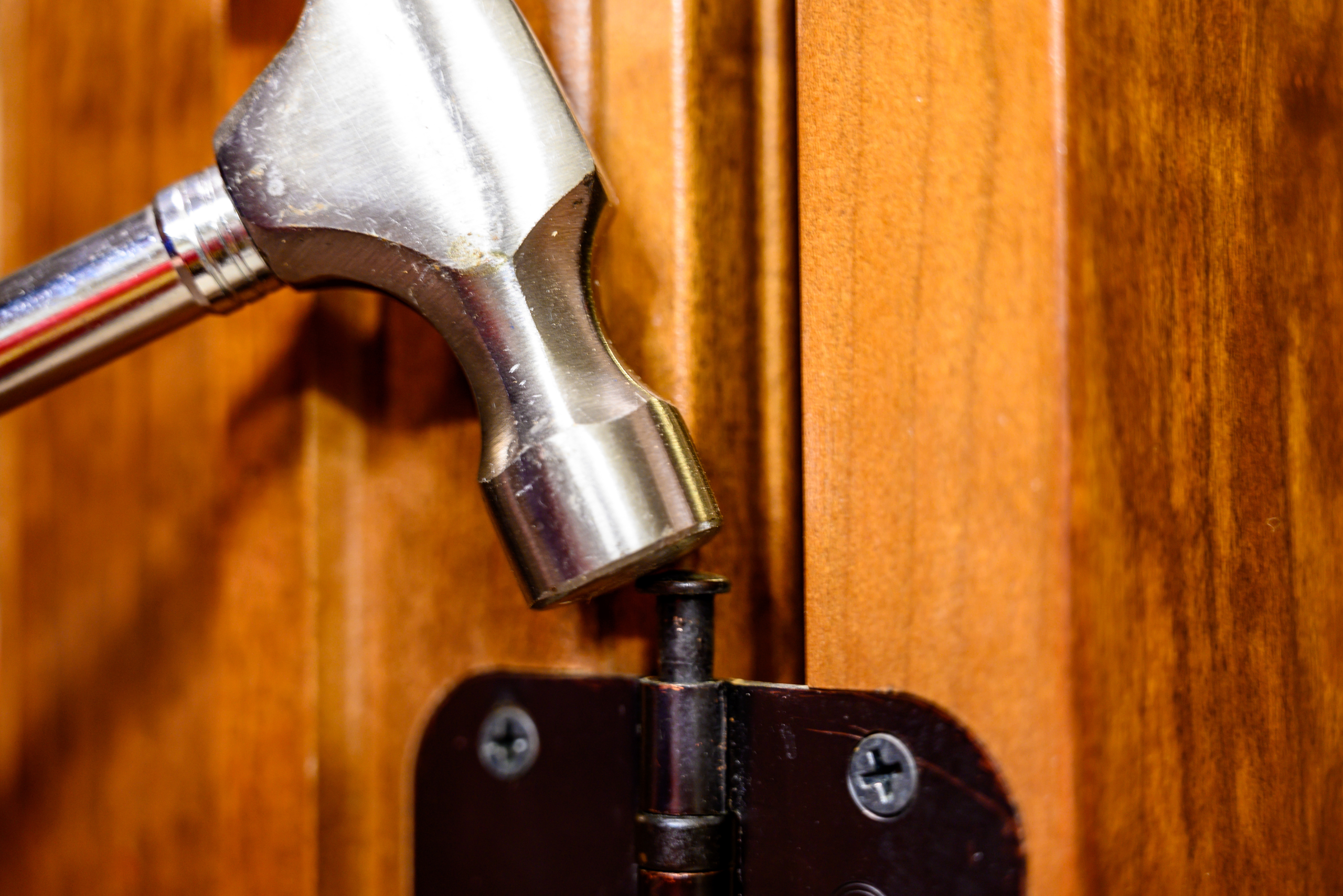 Hammer striking door pin back into its hinge.
