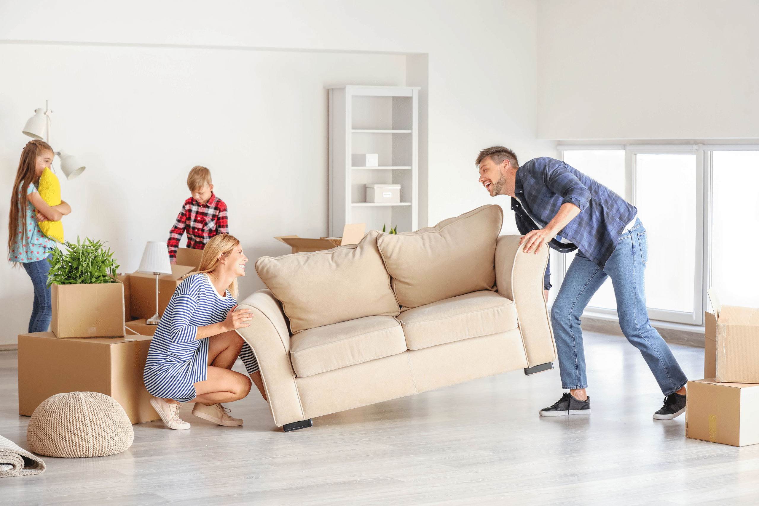 Couple lifting a couch with their kids in the background.