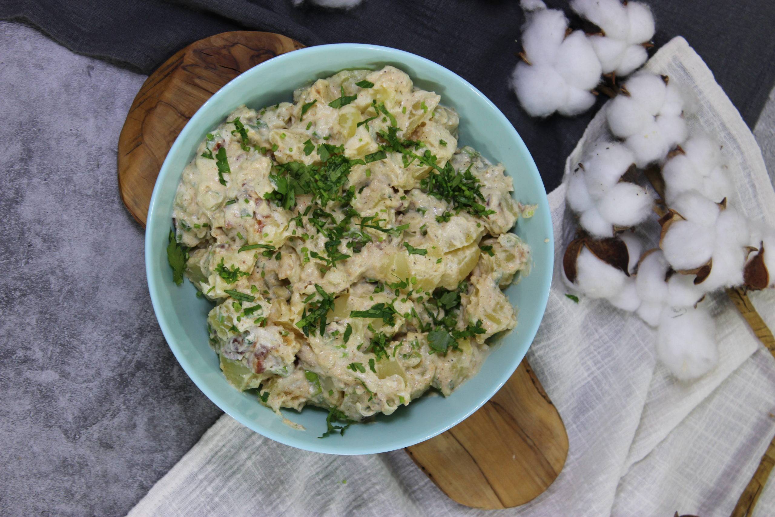 potato salad garnished in blue bowl on wooden serving platter