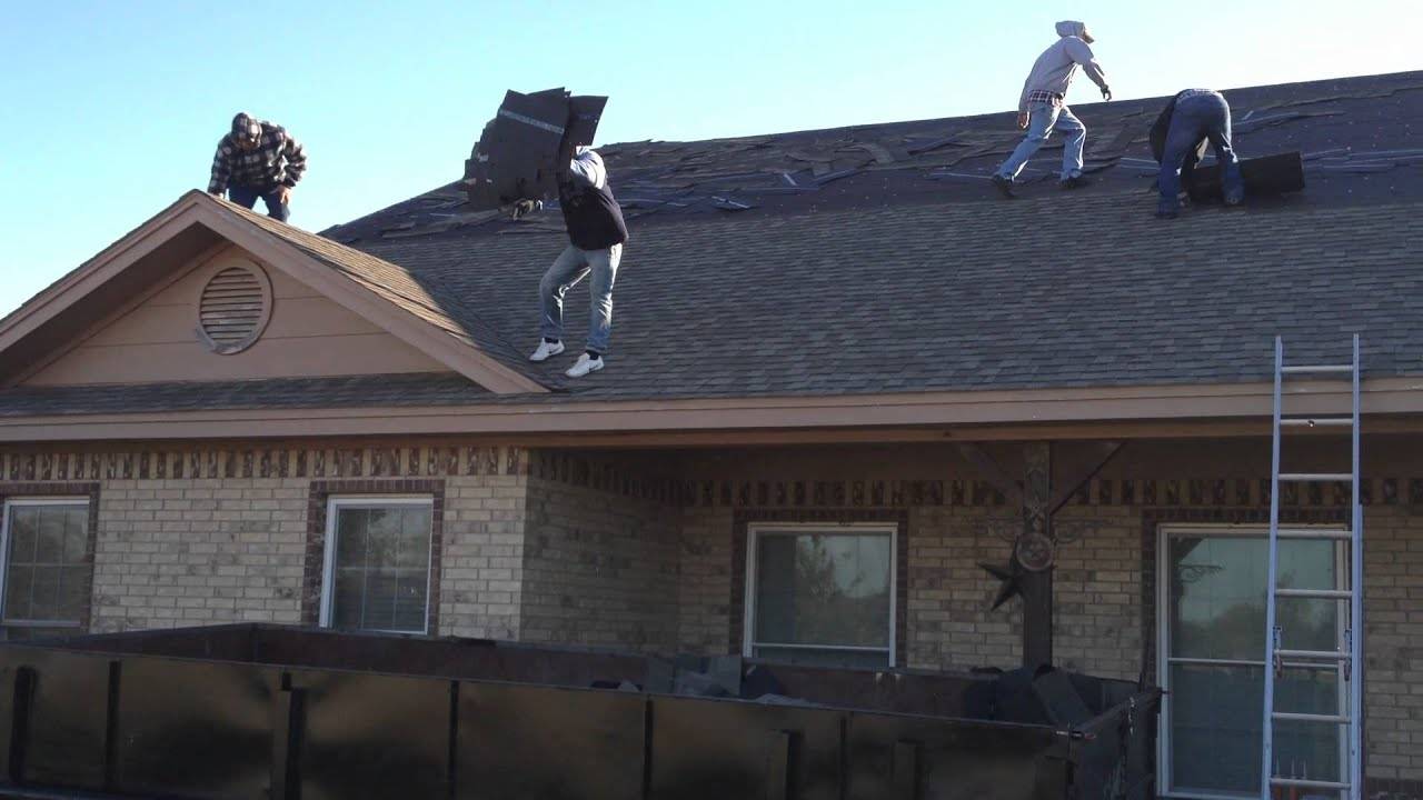 Roofers tossing shingles in a dumpster.