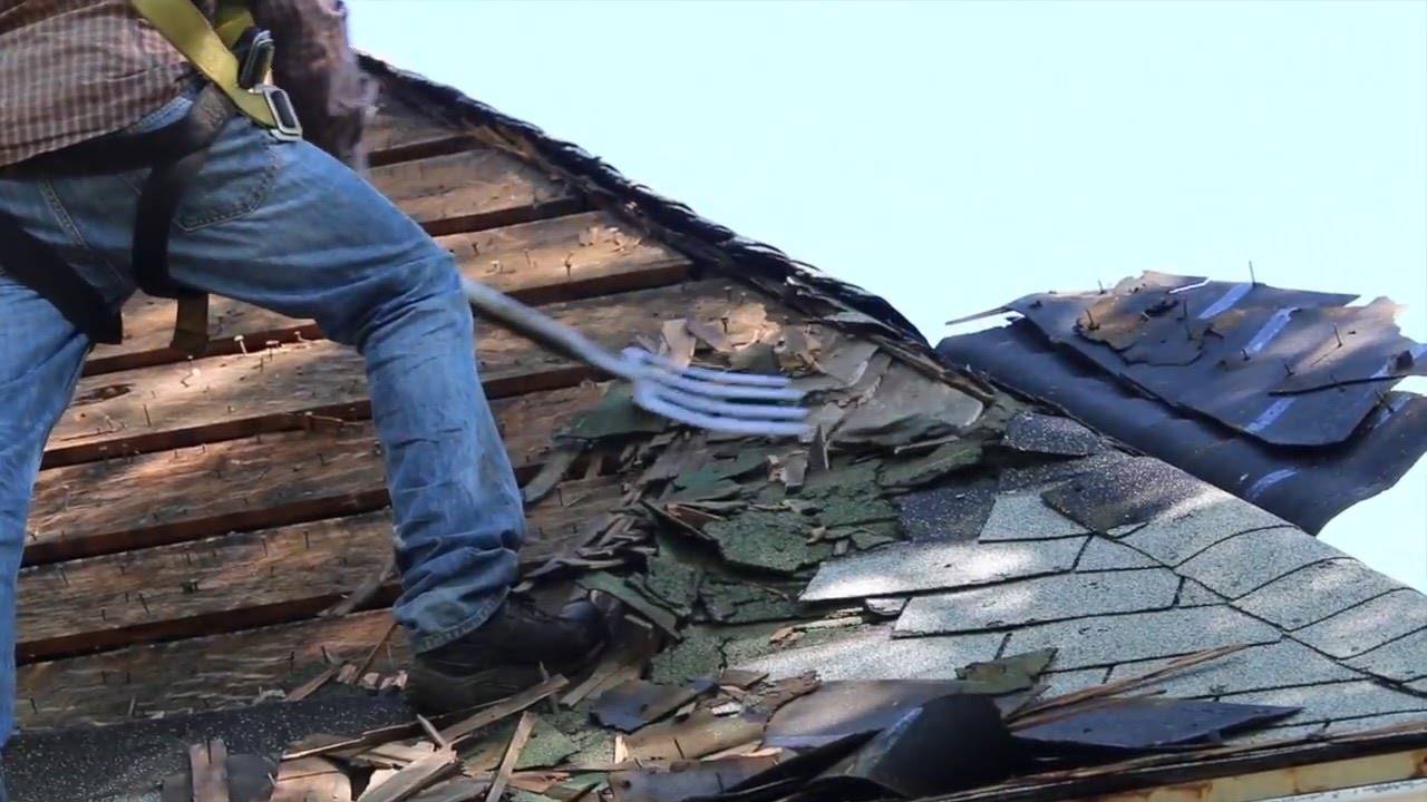 Roofer removing shingle using a pitch fork.
