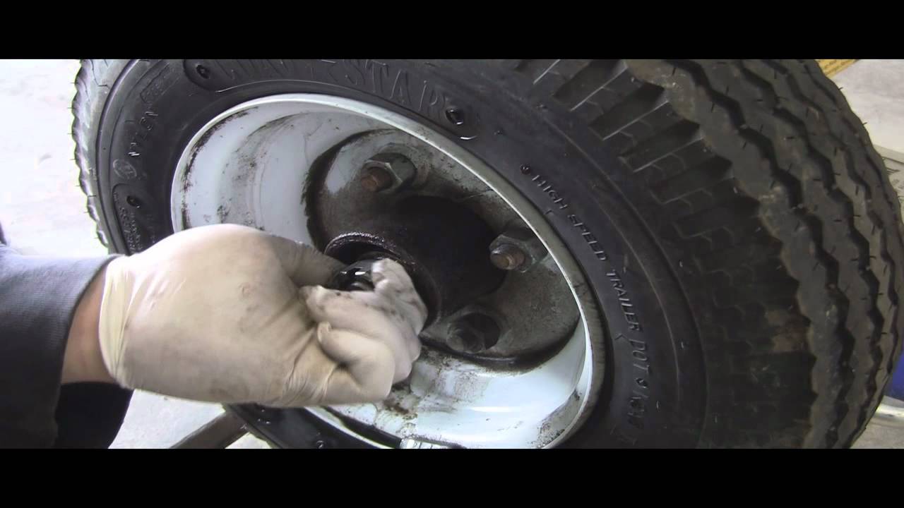 Person wearing latex gloves while removing a trailer axle cap.