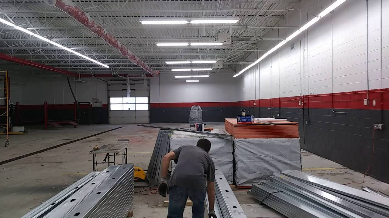 Worker grabbing metal stud from a stack of metal studs.