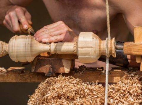 man using a lathe to carve wood