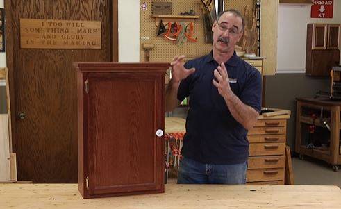 man next to a wooden cabinet