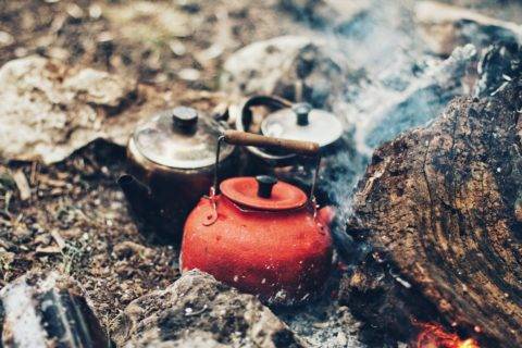 bowling kettles of water over fire while camping