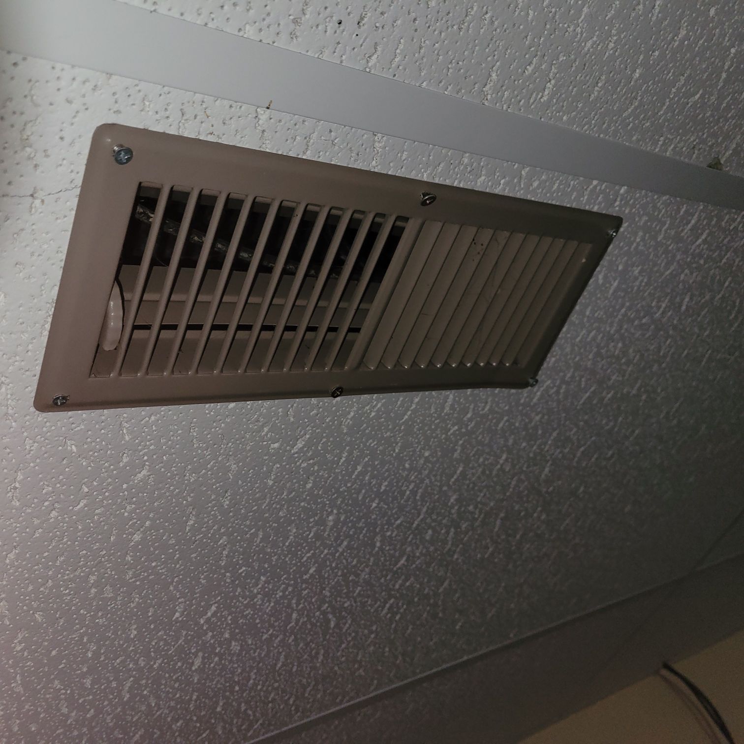 Closeup of drop ceiling tile with a vent mounted.