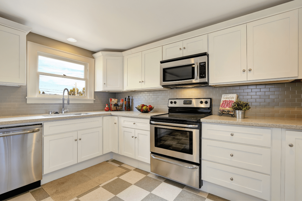 kitchen wide shot white cupboards microwave over stove stainless steel