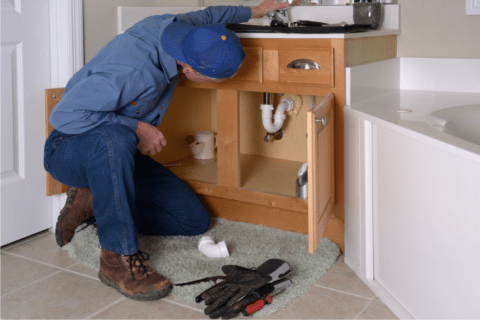 man in blue fixing a sink