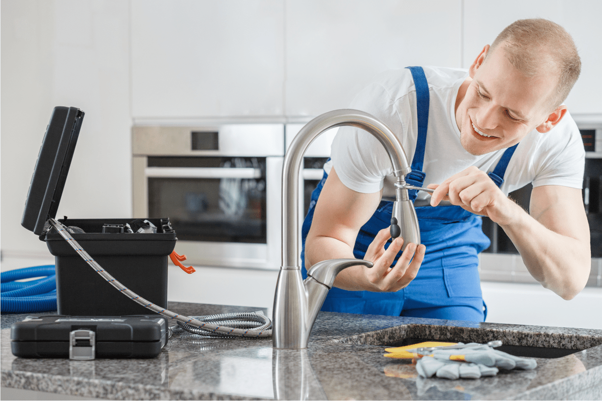man in blue overalls installing a faucet kitchen toolbox