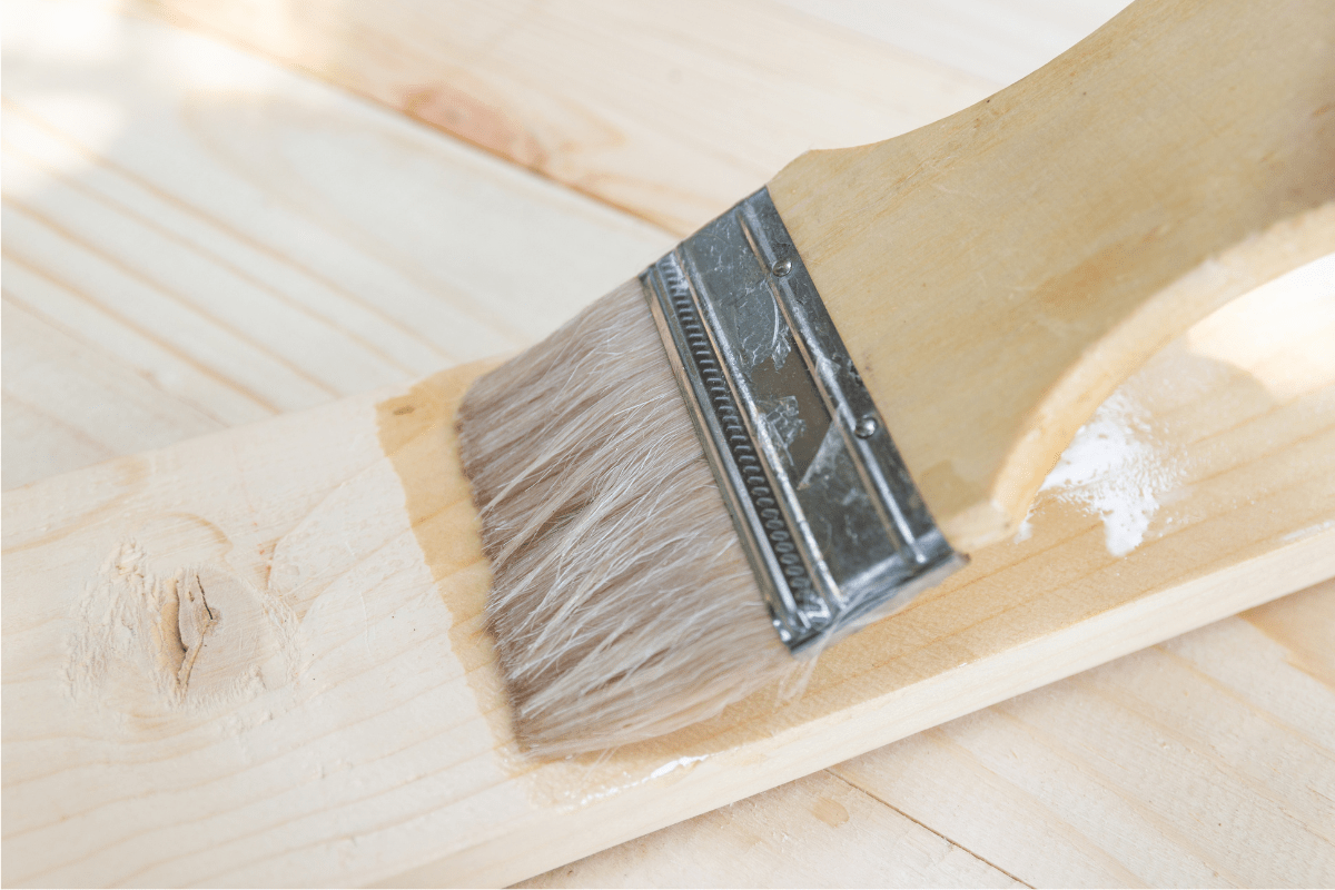 pale wood brush brushing on shellac on a piece of wood close up