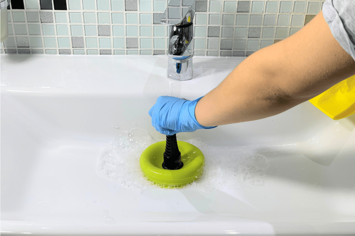 unclogging a sink with a green plunger