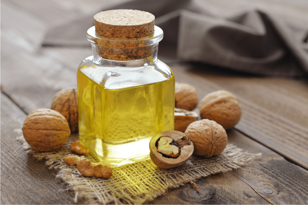 walnut oil close up glass jar wood background walnuts cork lid