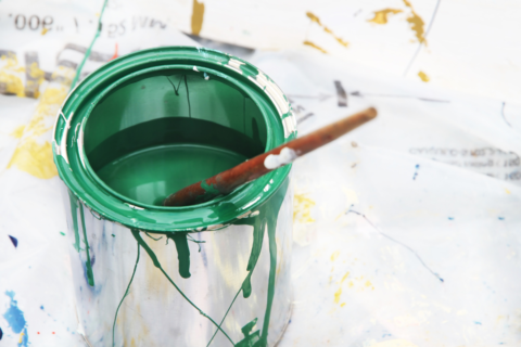 green open paint can on messy background brush inside