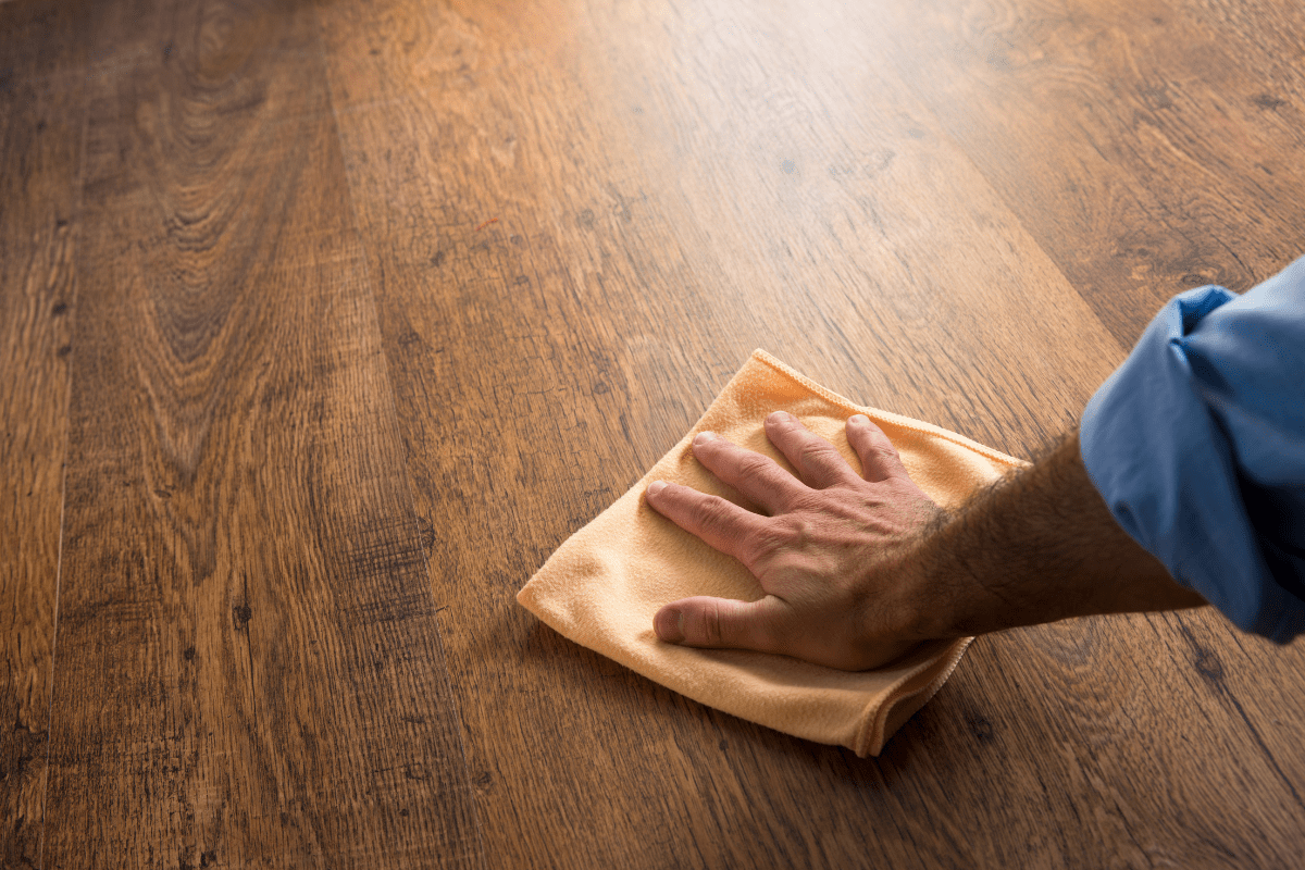 man wiping hardwood floor with microfibre towel