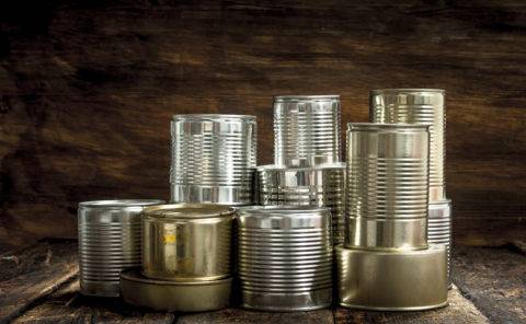 Food in tin cans. On a wooden background.