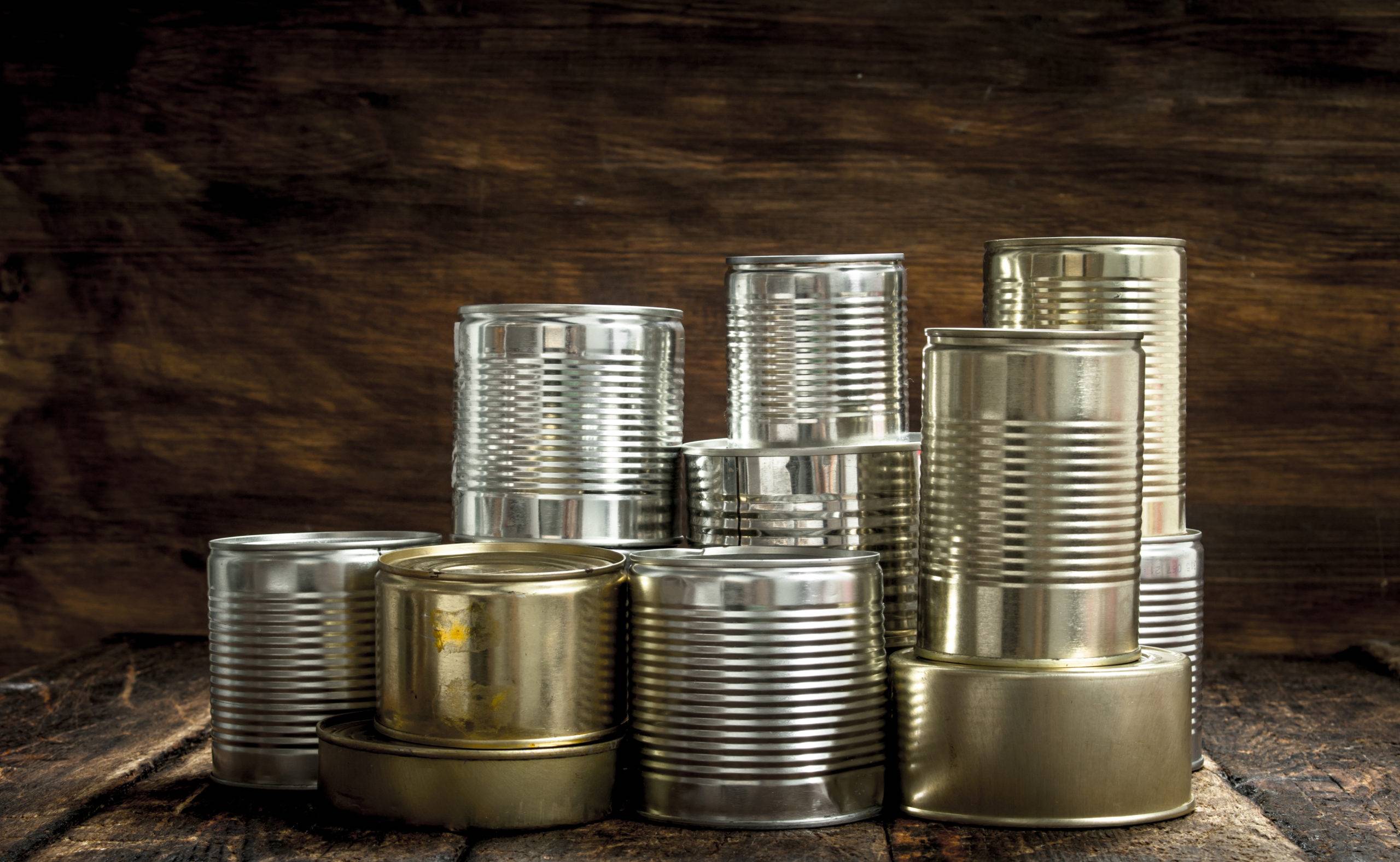 Food in tin cans. On a wooden background.