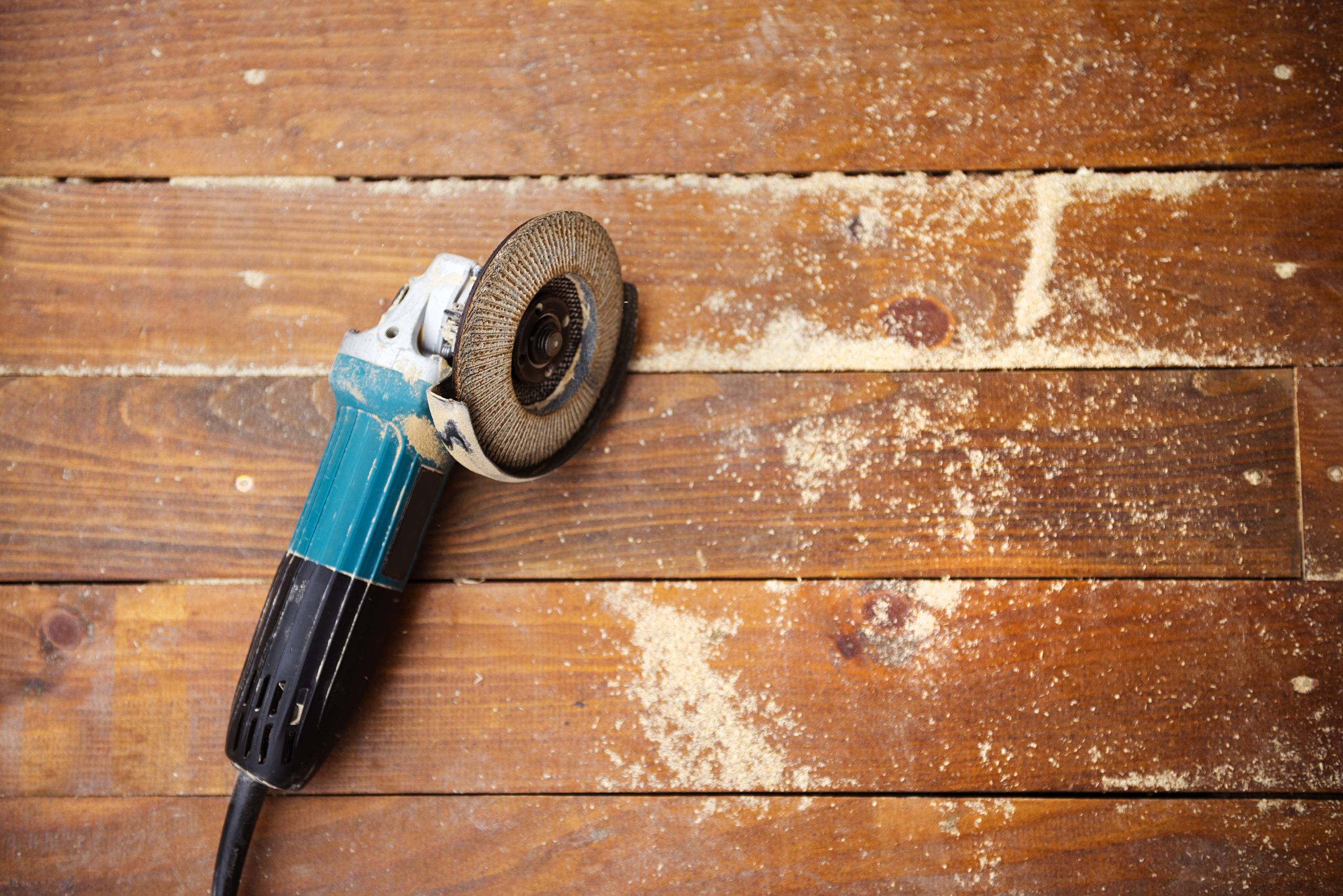 Electric grinder machine left on dusty wooden flooring with wood shavings