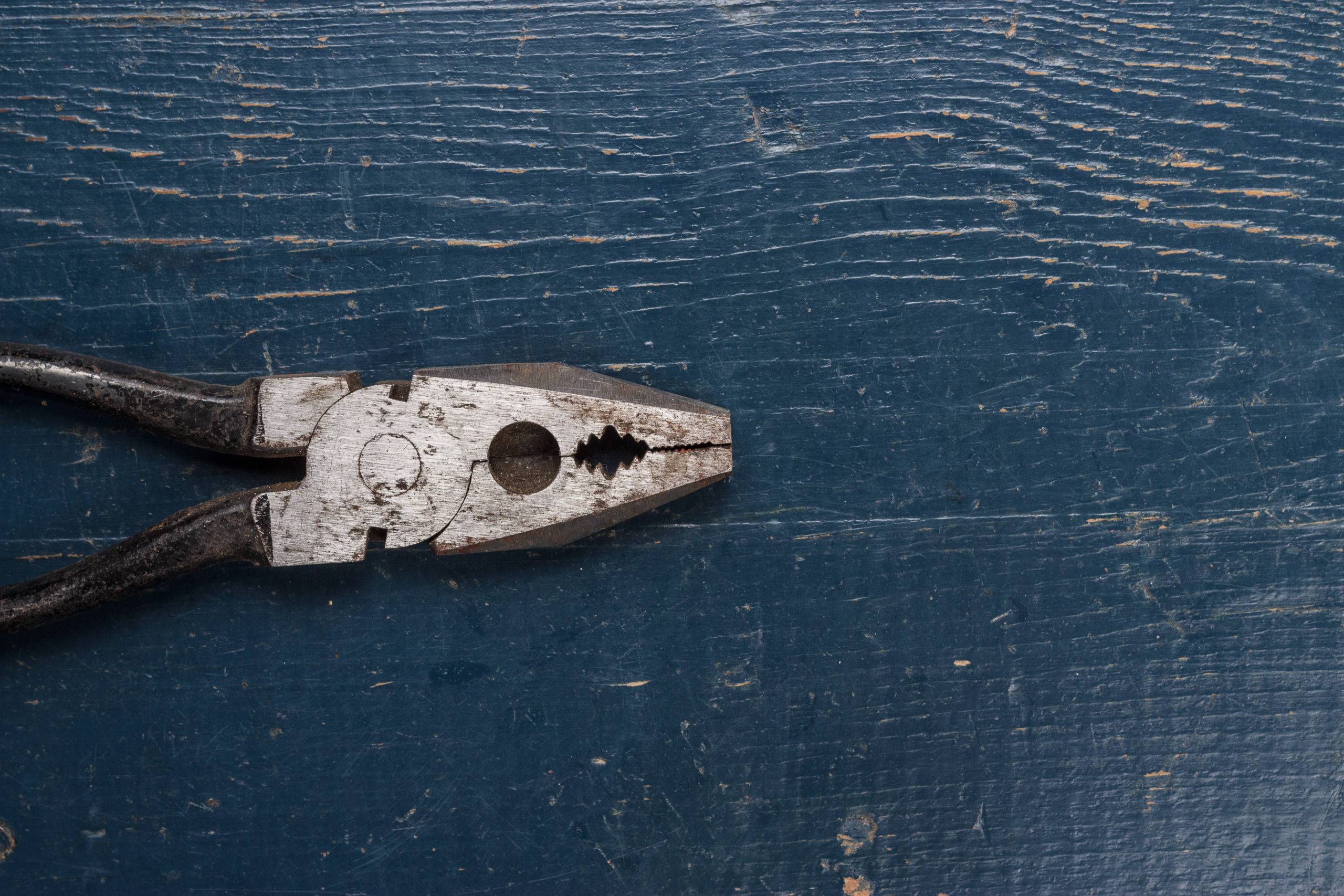 black pliers on the blue wooden background