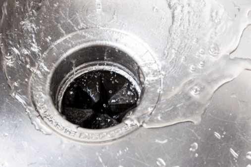 close up of garbage disposal running water stainless steel sink