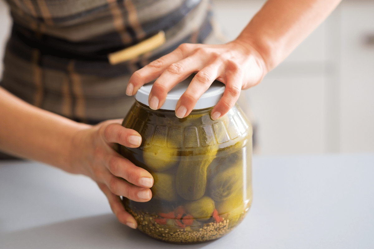 large pickle jar being opened on white counter tough to open women's hands