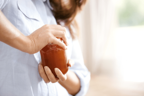 close up of woman trying to open a mason jar