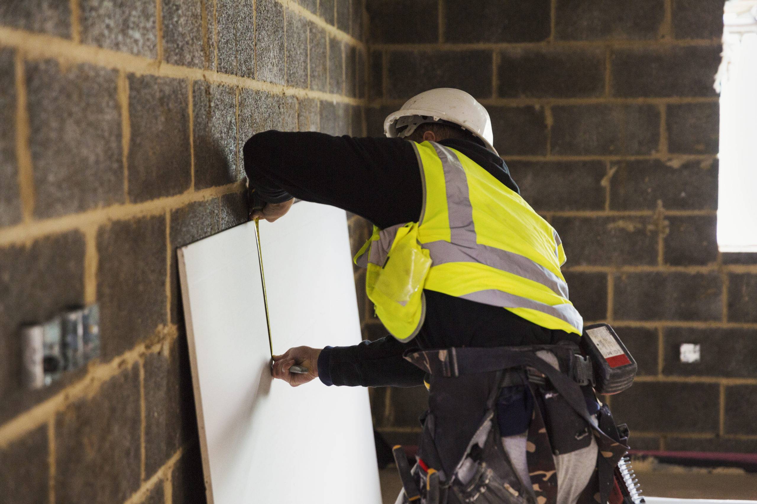 man in hard hat with tool belt and safety vest