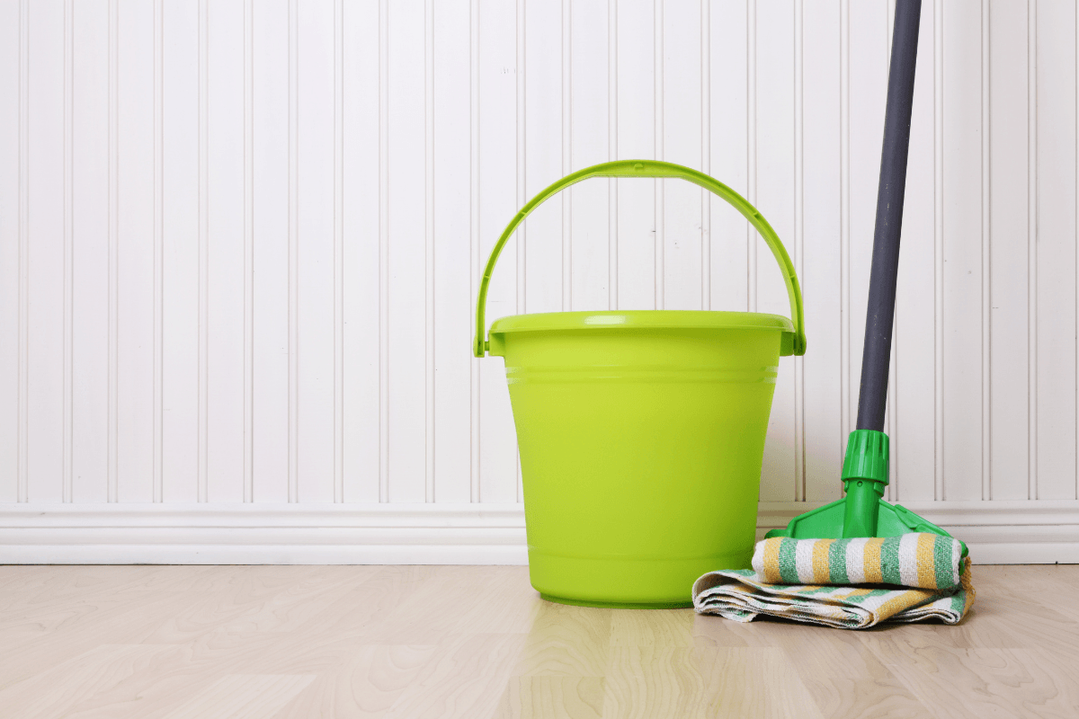lime green mop and bucket with board and batten wall white in background