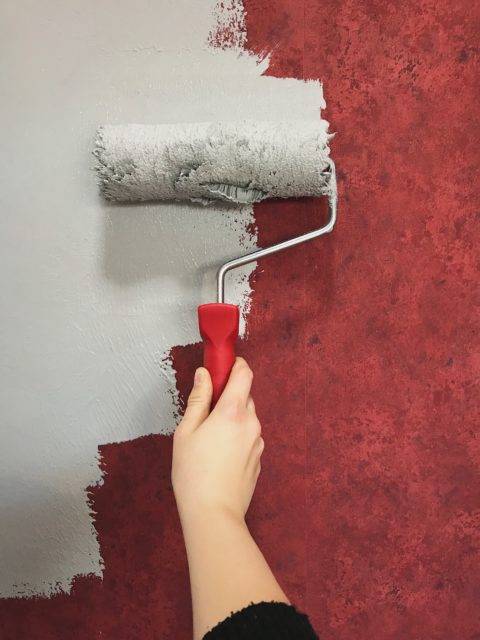 close up of woman's hand painting red wall