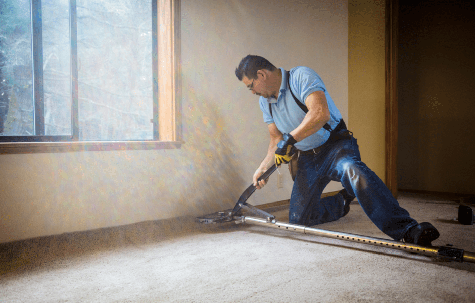 Using carpet jack to stretch carpet along baseboards