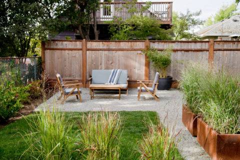 outdoor couch against light wood fence on grey stone patio