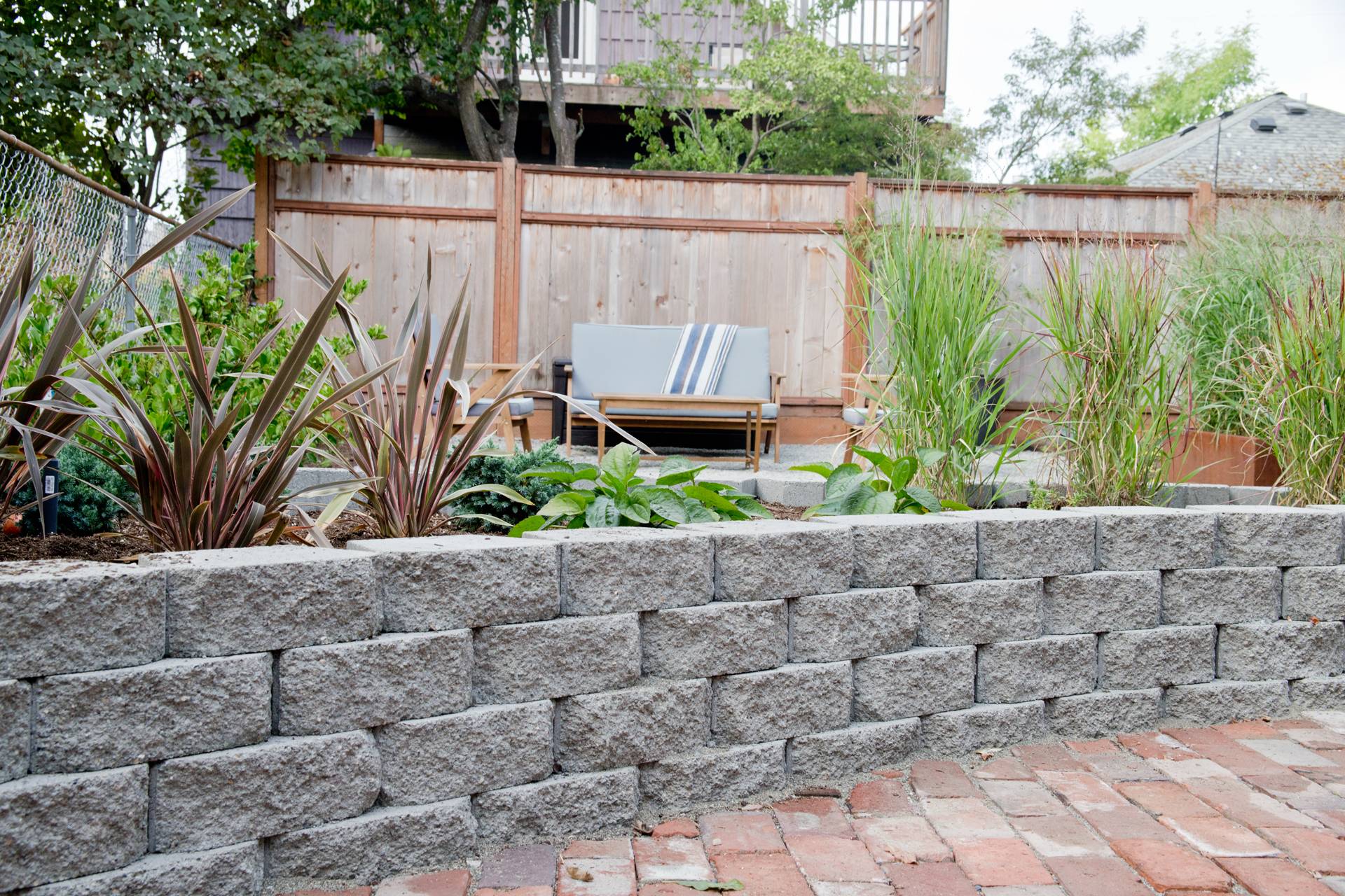 stone wall in foreground outdoors with couch in background on wooden fence