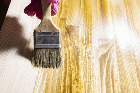 paint brush with wood stain covering plain wood board