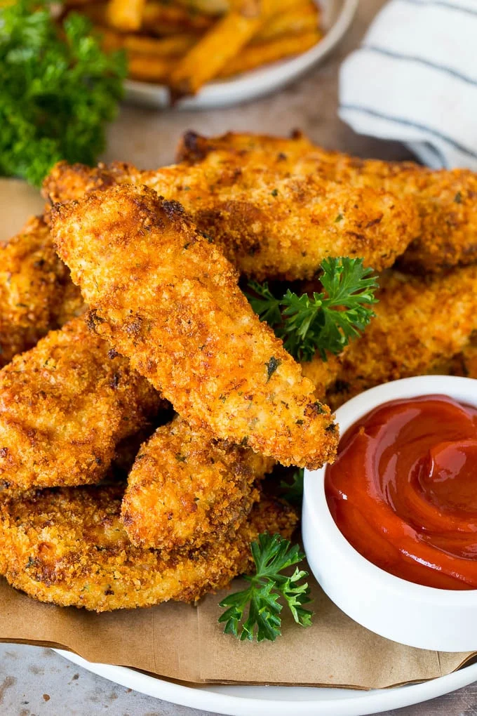 crispy chicken tenders on plate with ketchup and green garnish
