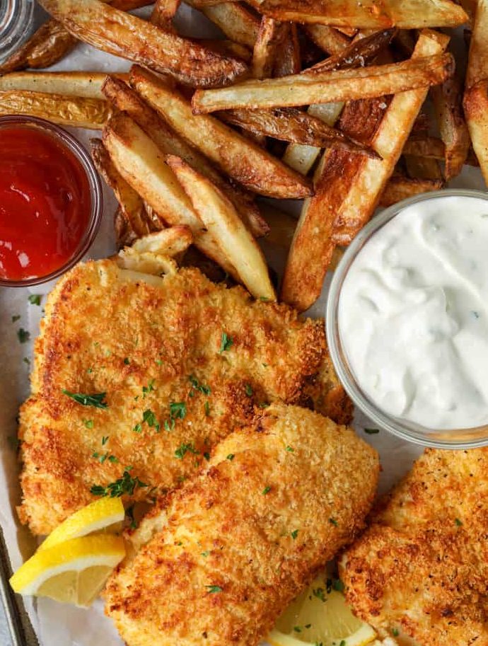 crispy fried fish pieces with tartar sauce and fries on plate with ketchup