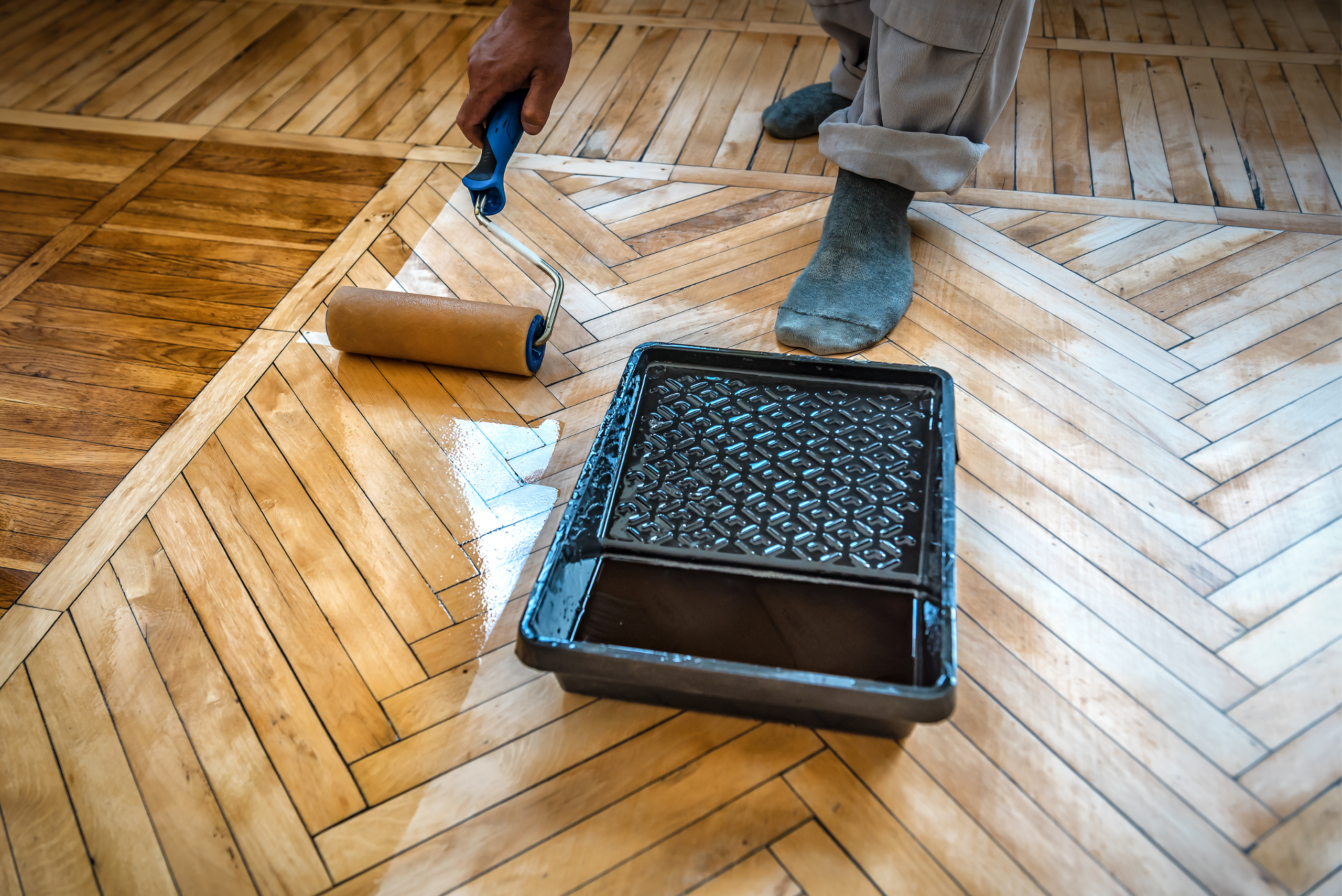 Person using a roller to seal wood floor